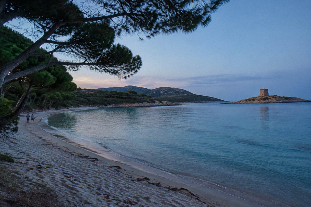 A near-circular bay of pale sand framed by low maquis hills
